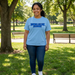Person wearing a light blue t-shirt with 'Edwin Allen Alumni' text in a park setting Edwin Allen High School Alumni Shirt - Crest Back - EAHS Alumni Apparel